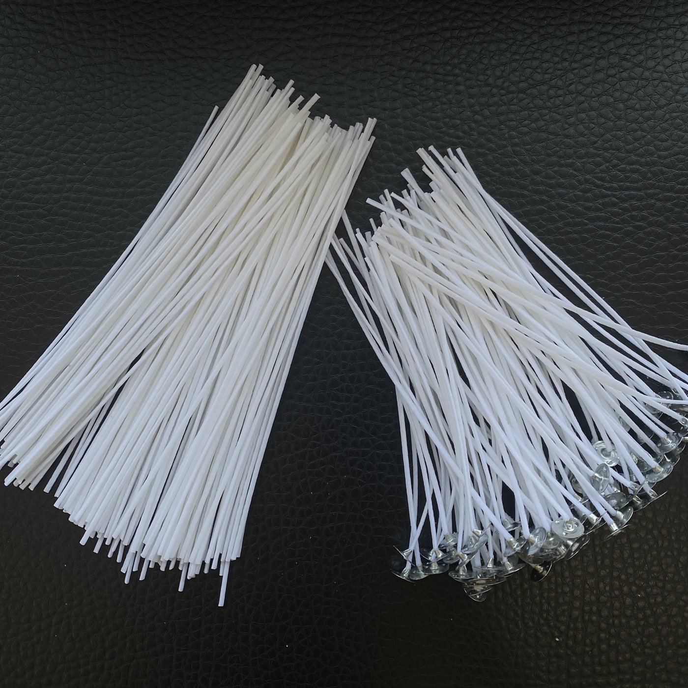 Two bundles of white cotton candle wicks, one plain and one fitted with metal sustainer tabs