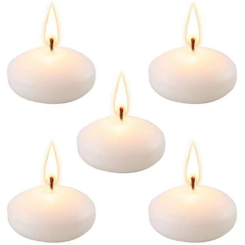 Five white round floating candles with lit wicks