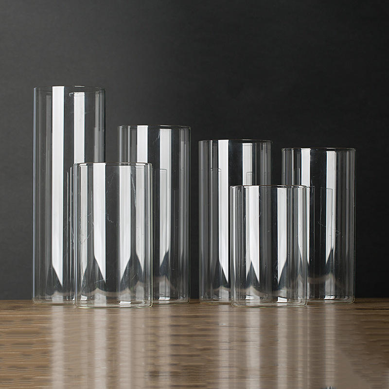 Six clear glass cylinder jars and vases in different heights on a wooden table