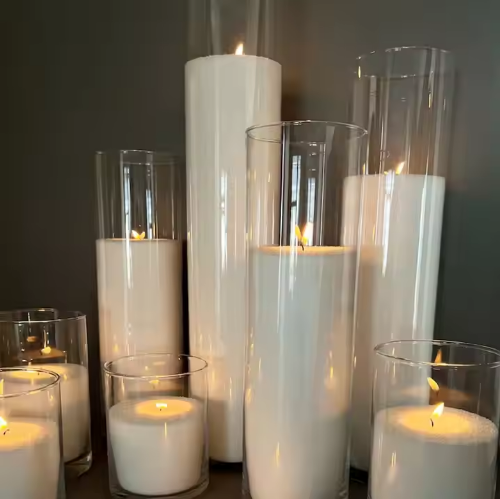 A tall clear glass vase designed to hold a sand wax fill