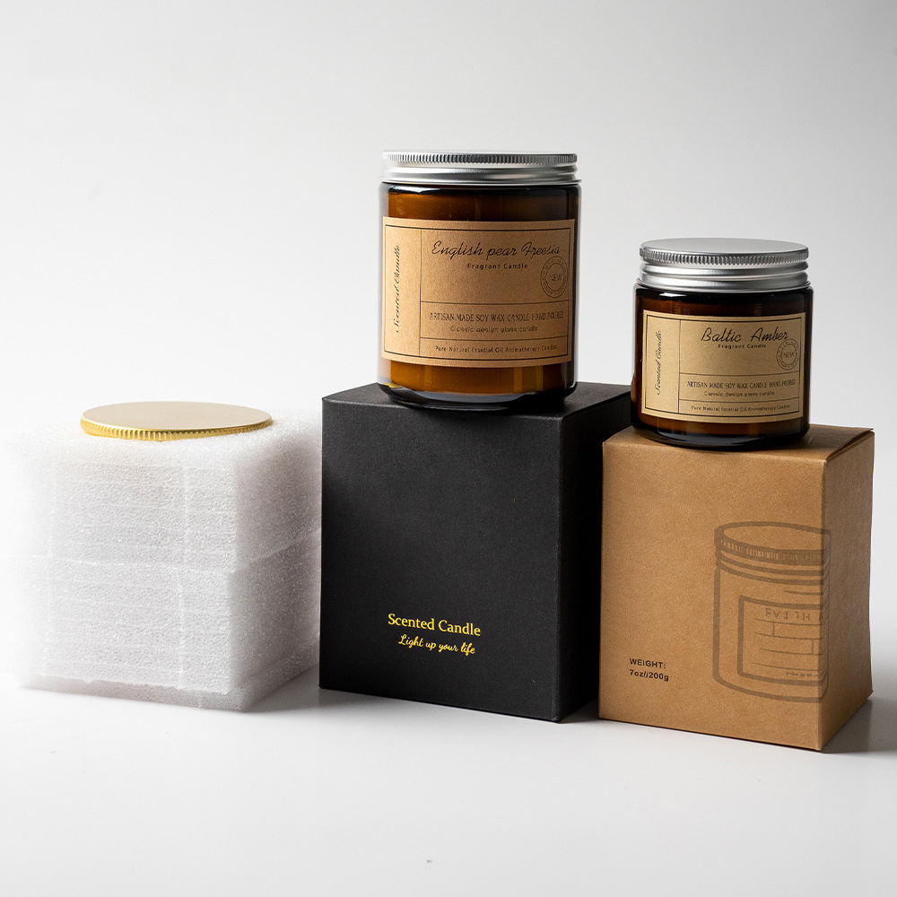 Two private label soy candles in amber glass jars with metal lids beside their gift boxes