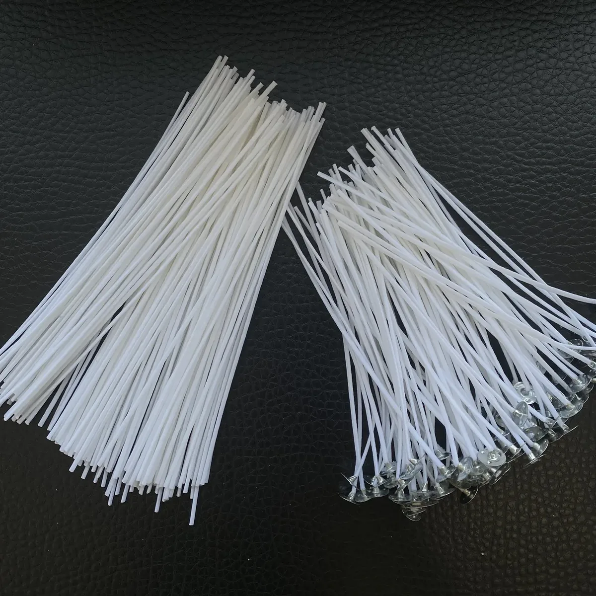 Two bundles of white cotton candle wicks, one plain and one fitted with metal sustainer tabs